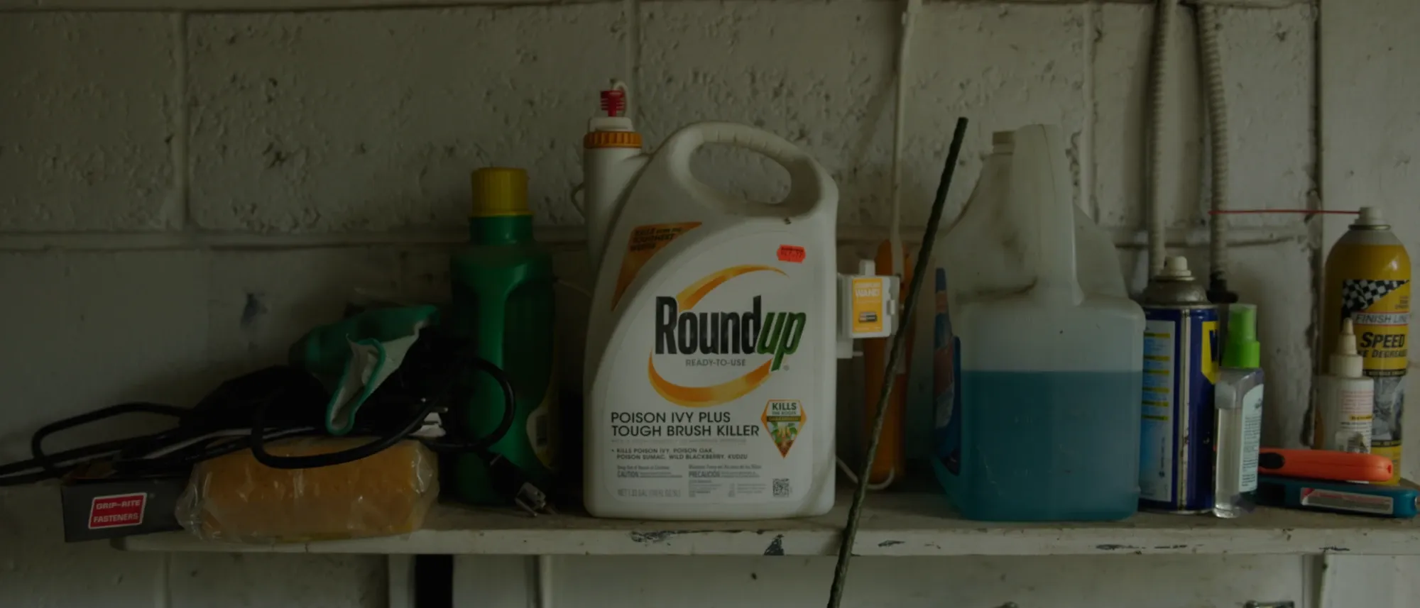 A jug of Roundup herbicide on a cluttered garage shelf
